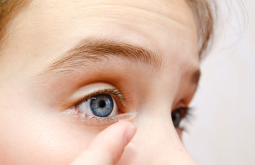 Woman applying contact lense to help control myopia